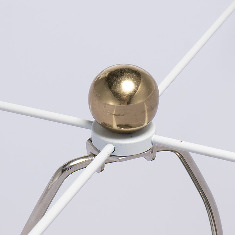 Close-up of a decorative table lamp with a gold sphere and white spokes on a light gray background