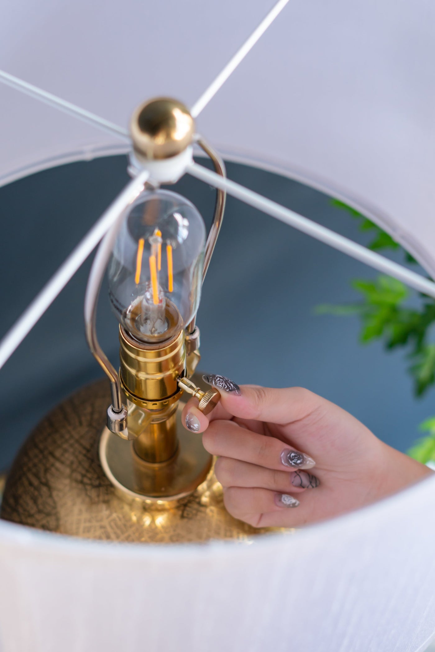 Hand holding a vintage-style light bulb with a gold base against a blurred background