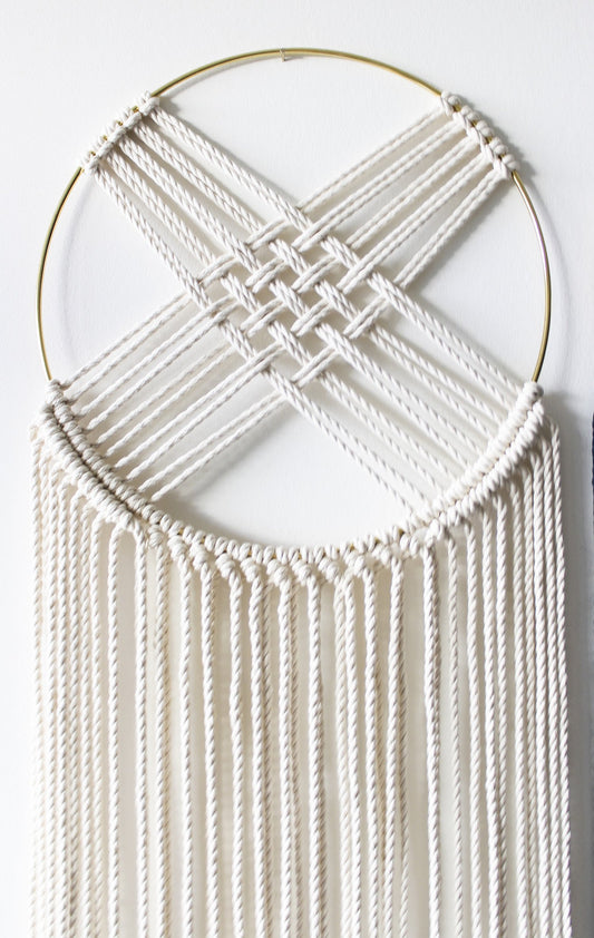 Macrame dreamcatcher wall hanging with gilded brass hoop and long ivory fringe.