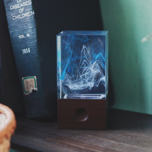 Resin lamp with blue light on a shelf next to a book