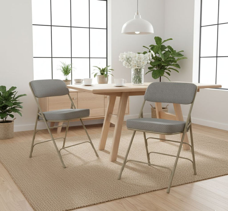 Two gray chairs in front of a wooden dining table with plants and a lamp in a bright room.
