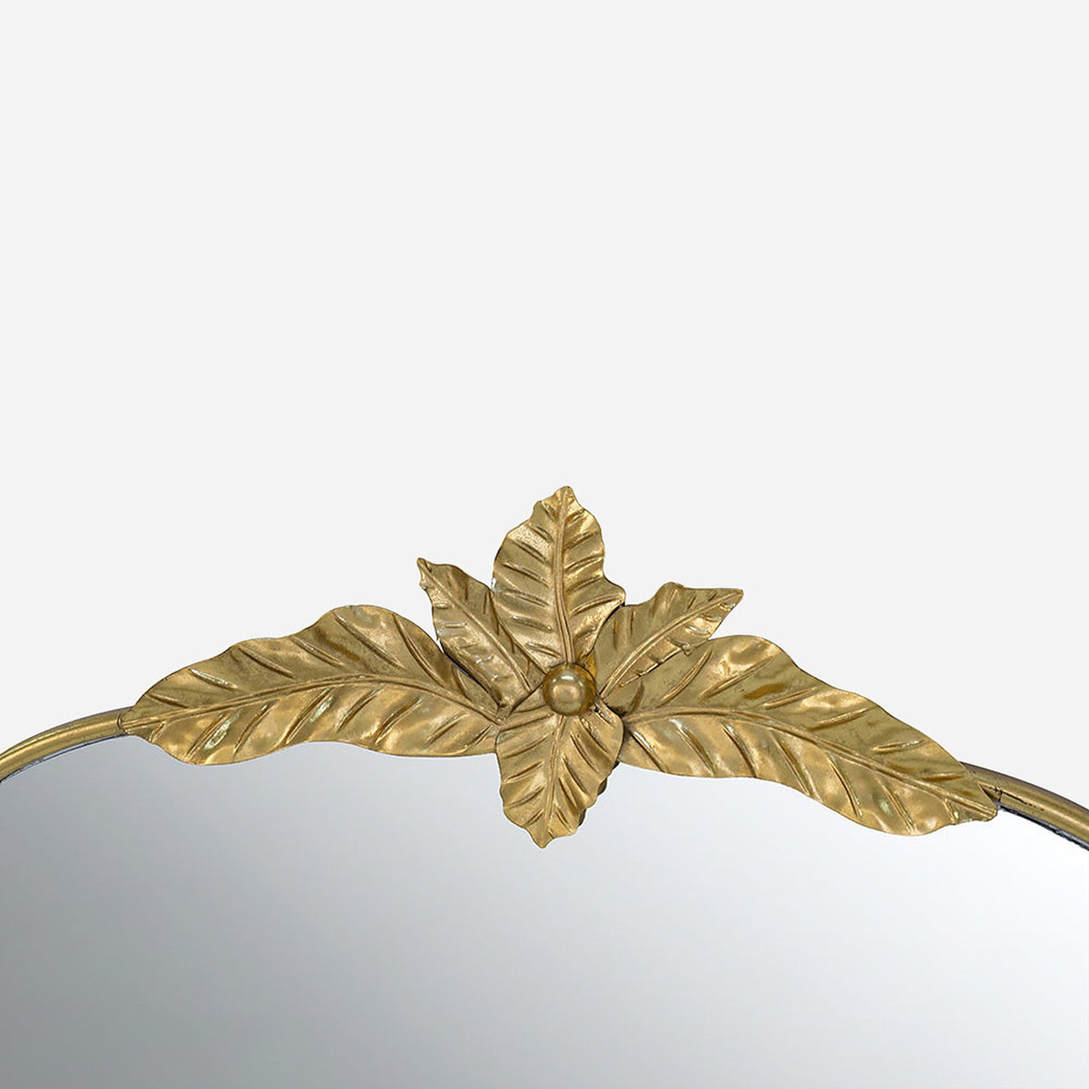 Gilded leaf crest at the top of a slim gold iron mirror frame, close-up detail