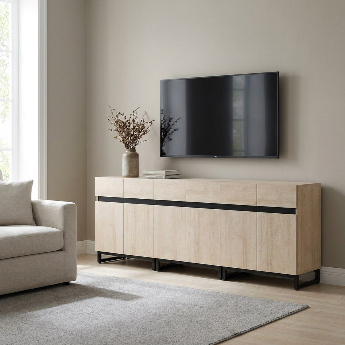 Light oak handleless media console under a wall-mounted TV in a bright living room