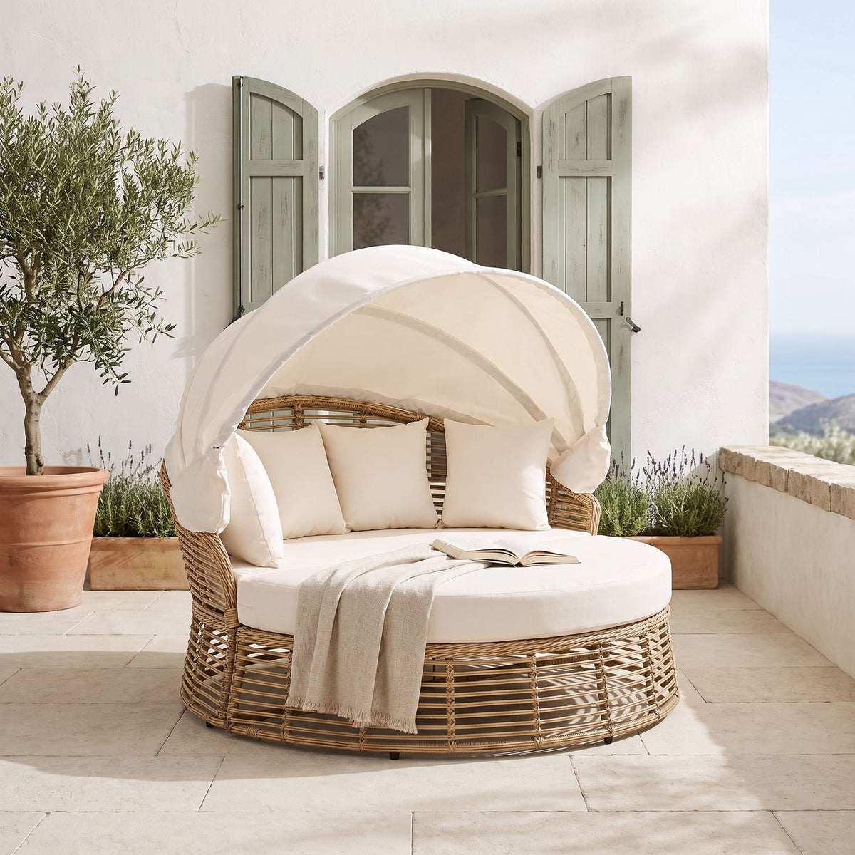 Round wicker daybed with canopy on a sunlit Mediterranean terrace