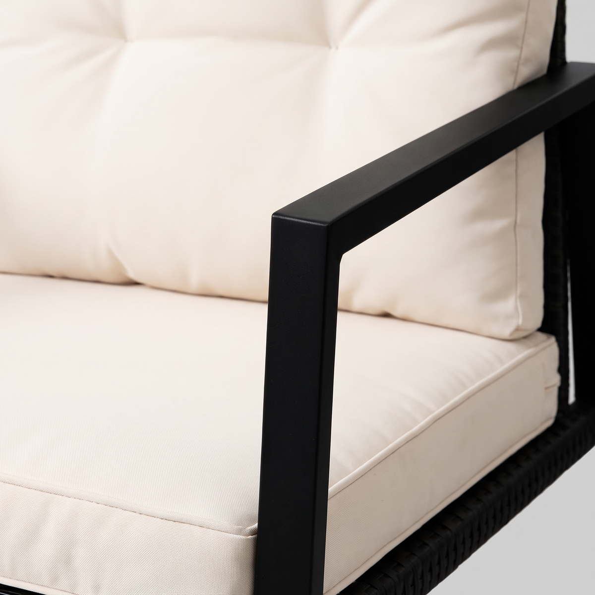 Close-up of the cream tufted cushion inside the slim black steel arm