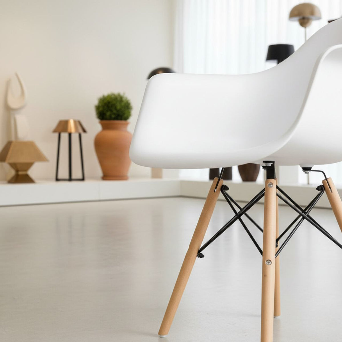 White molded mid-century dining arm chair with natural wood legs and black metal cross supports.