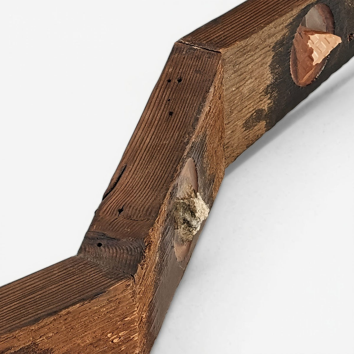 Close-up of an angled joint between two wood sections with a white tile sample