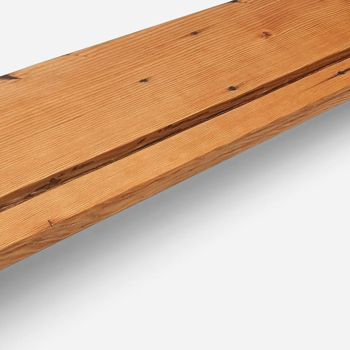 Long slot groove along the front edge of natural oiled wood with knots either side (close-up detail)