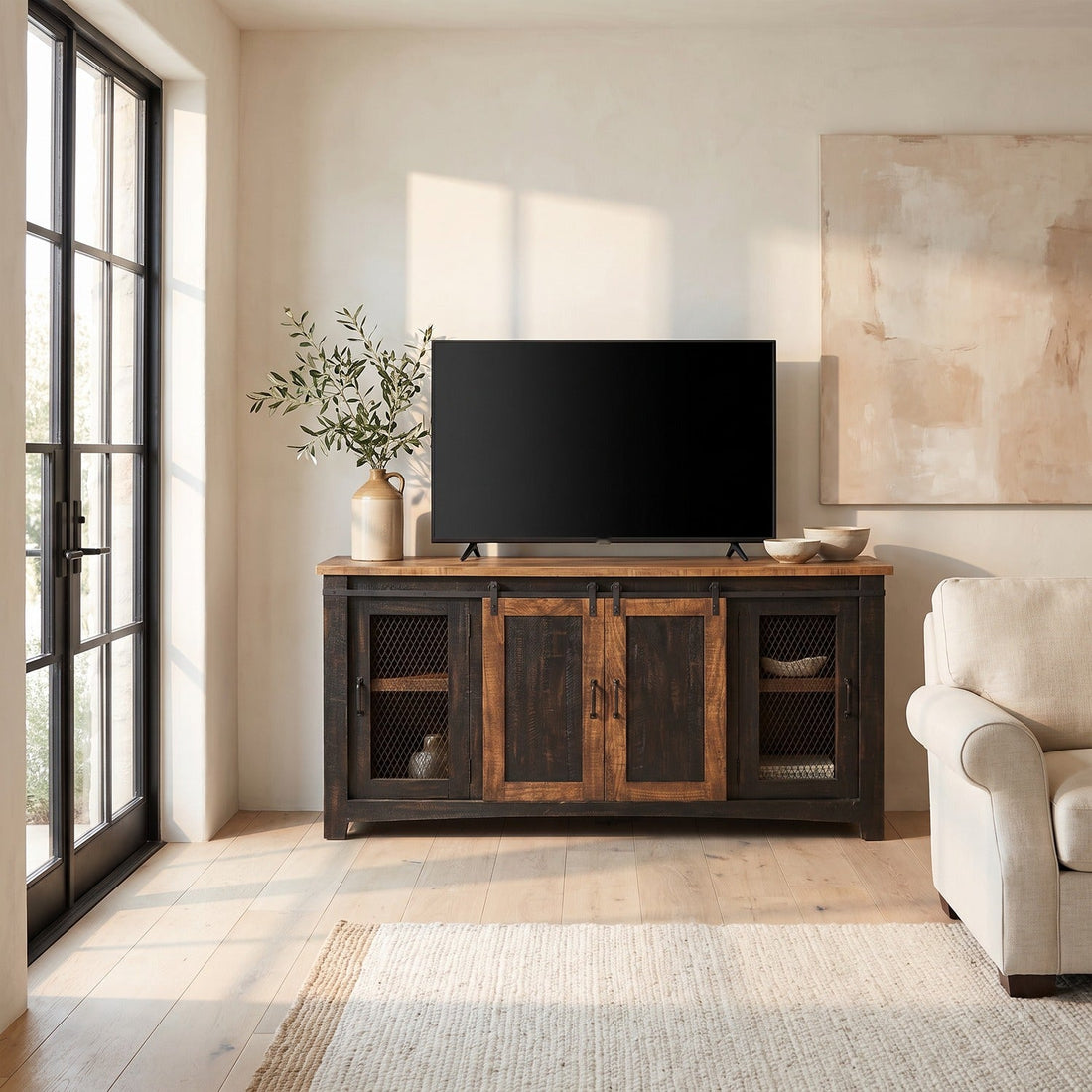 Barn door TV stand supporting a 65-inch TV in a sunlit farmhouse family room beside tall French doors