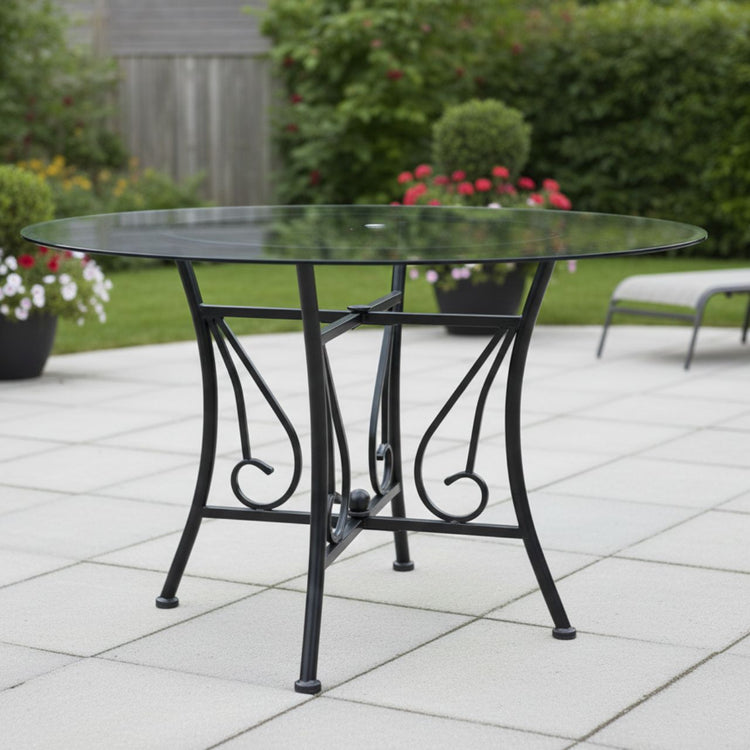 48-inch round clear glass dining table with a black powder-coated metal pedestal base and an 8mm tempered top on an outdoor patio.