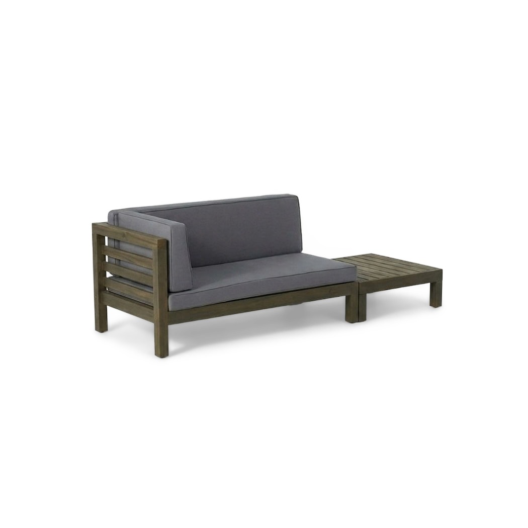 Acacia wood loveseat with dark grey cushions and slatted coffee table, angled view (plain studio)
