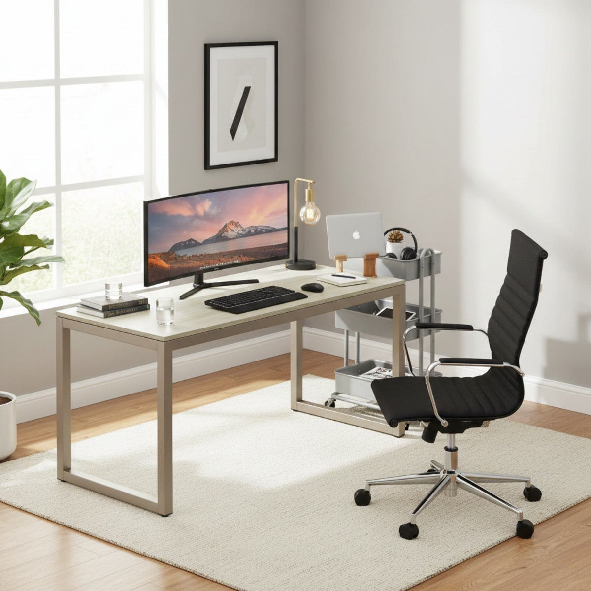 The desk under a window in a bright workroom, ultrawide monitor and keyboard on the top, plant and framed print behind