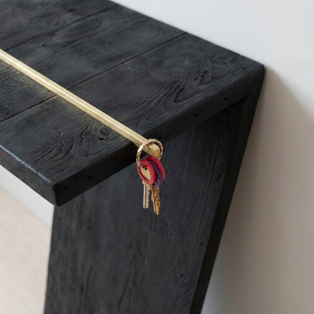 close-up detail of the brass rod end with keys where the top meets the upright, entryway wall behind