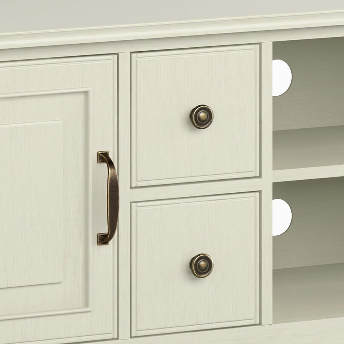 Drawer fronts with round bronze ring knobs beside the cable holes of the open bay (close-up detail)