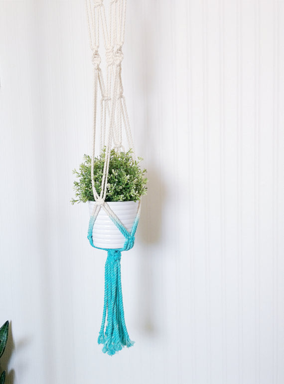 Aquamarine dip-dye macrame plant hanger, handmade in Canada, holding a white pot with a green plant.
