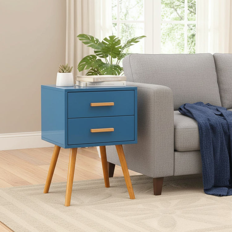 Blue finish modern classic end table with two drawers and angled wooden legs beside a gray sofa.