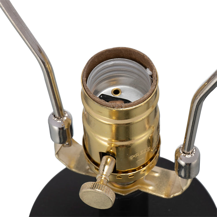 Close-up of a brass lamp socket with metal arms on a white background