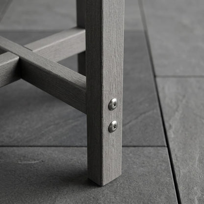 Close-up of a gray wooden outdoor chair leg with two silver screws fastened onto a dark gray tiled floor.