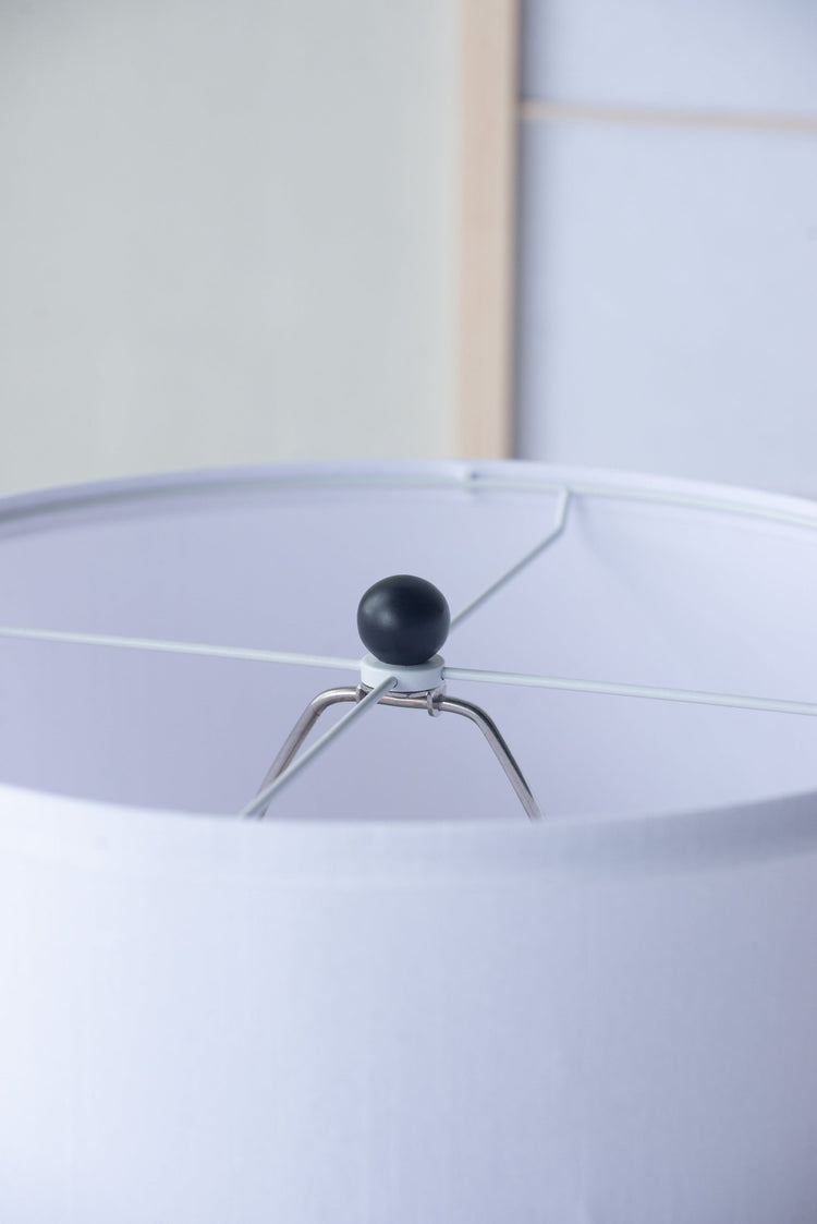 Close-up of a lampshade with a black finial on a white background