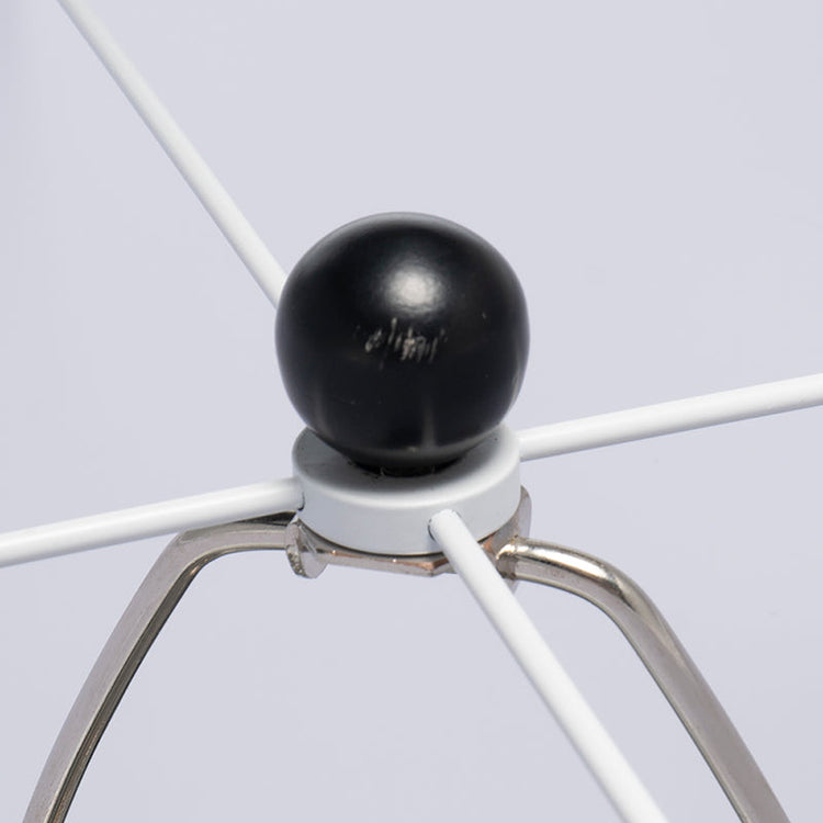 Close-up of a metal whisk with a black ball attachment on a light gray background