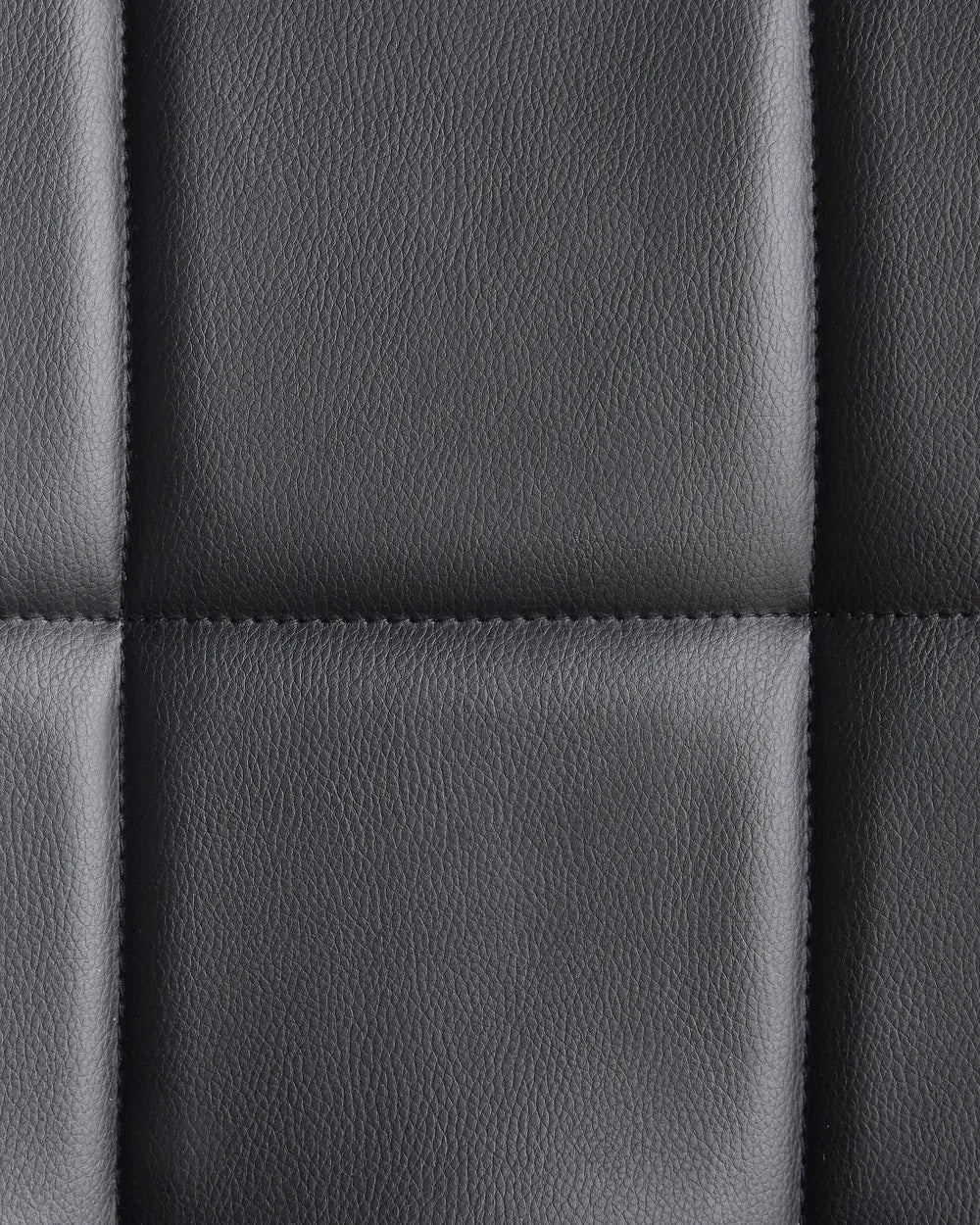 Close-up of a quilted black PVC leather cushion from a modern home office desk chair.