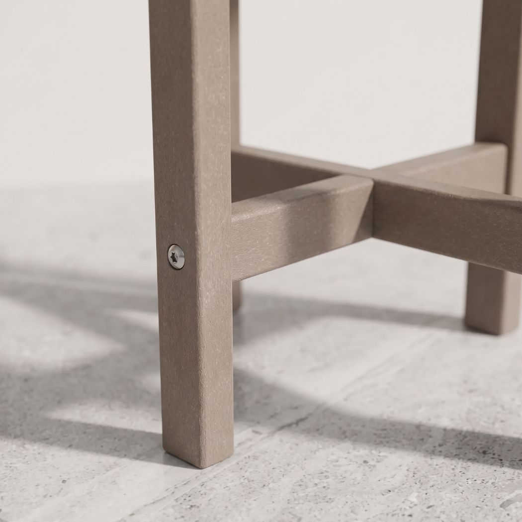 Close-up of a taupe-brown wooden table leg and cross-brace support on a light gray concrete floor.