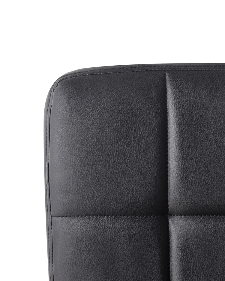 Close-up of black quilted faux leather cushion on a modern home office desk chair