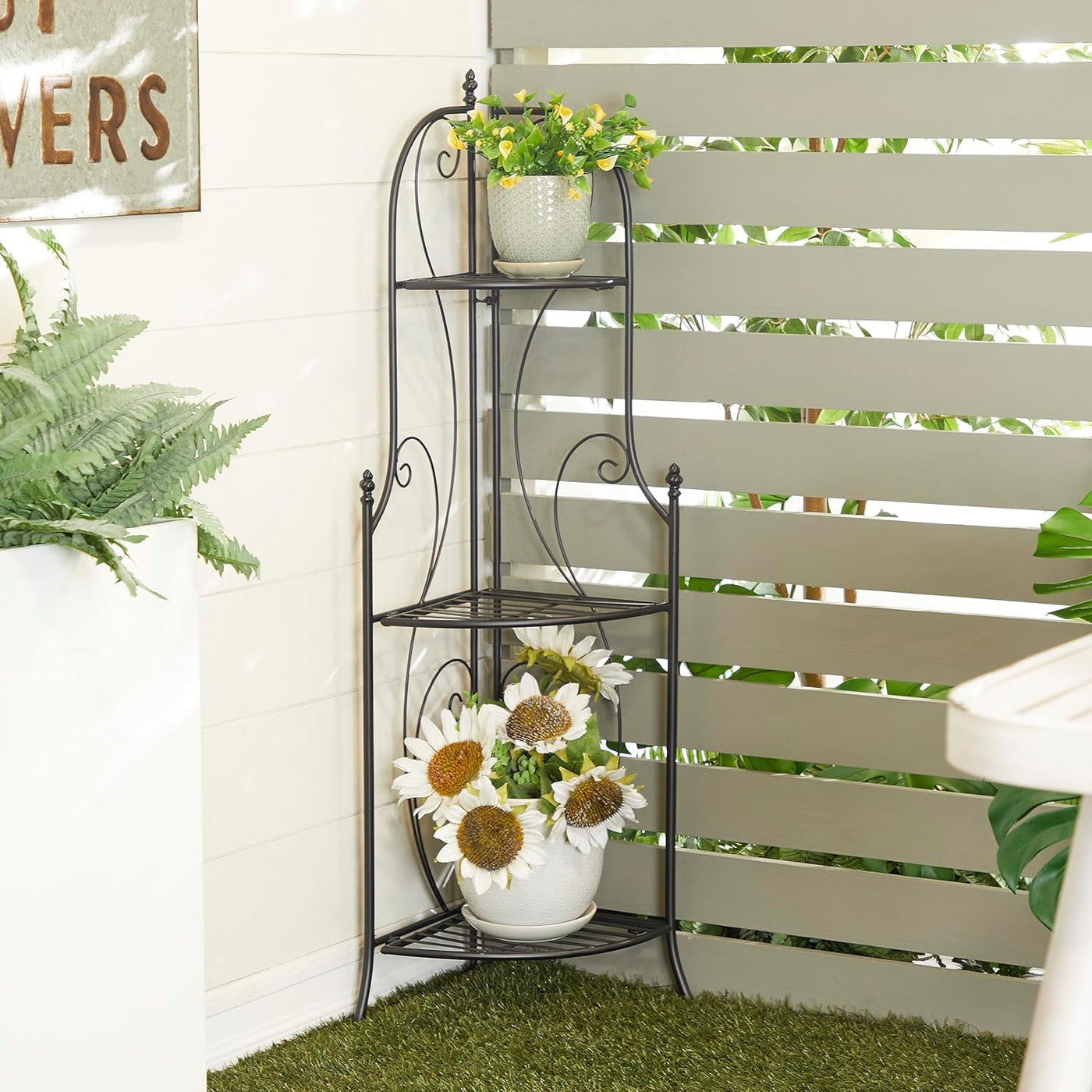 Decorative metal plant stand with potted plants against a white wall.