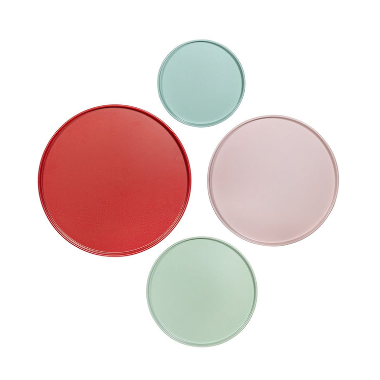 Four round ceramic plates in red, green, and pink on a white background