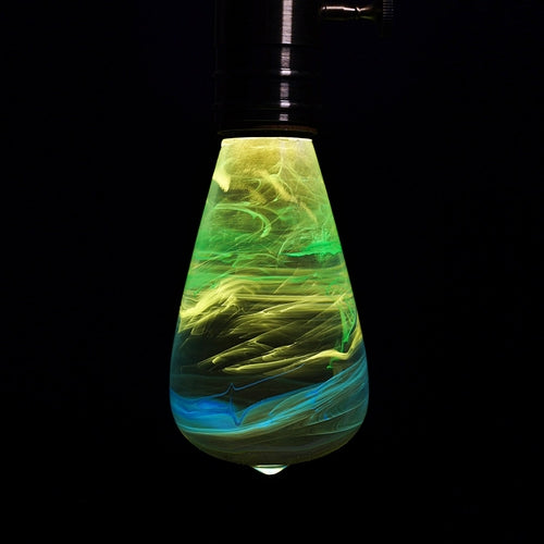 Glowing green and blue light bulb against a black background