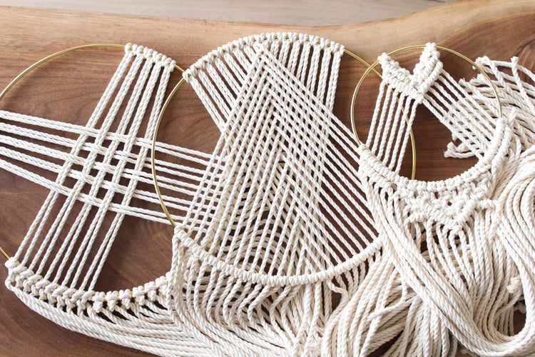 Macrame dreamcatcher wall hanging with a gilded brass hoop and intricate knotted cords.
