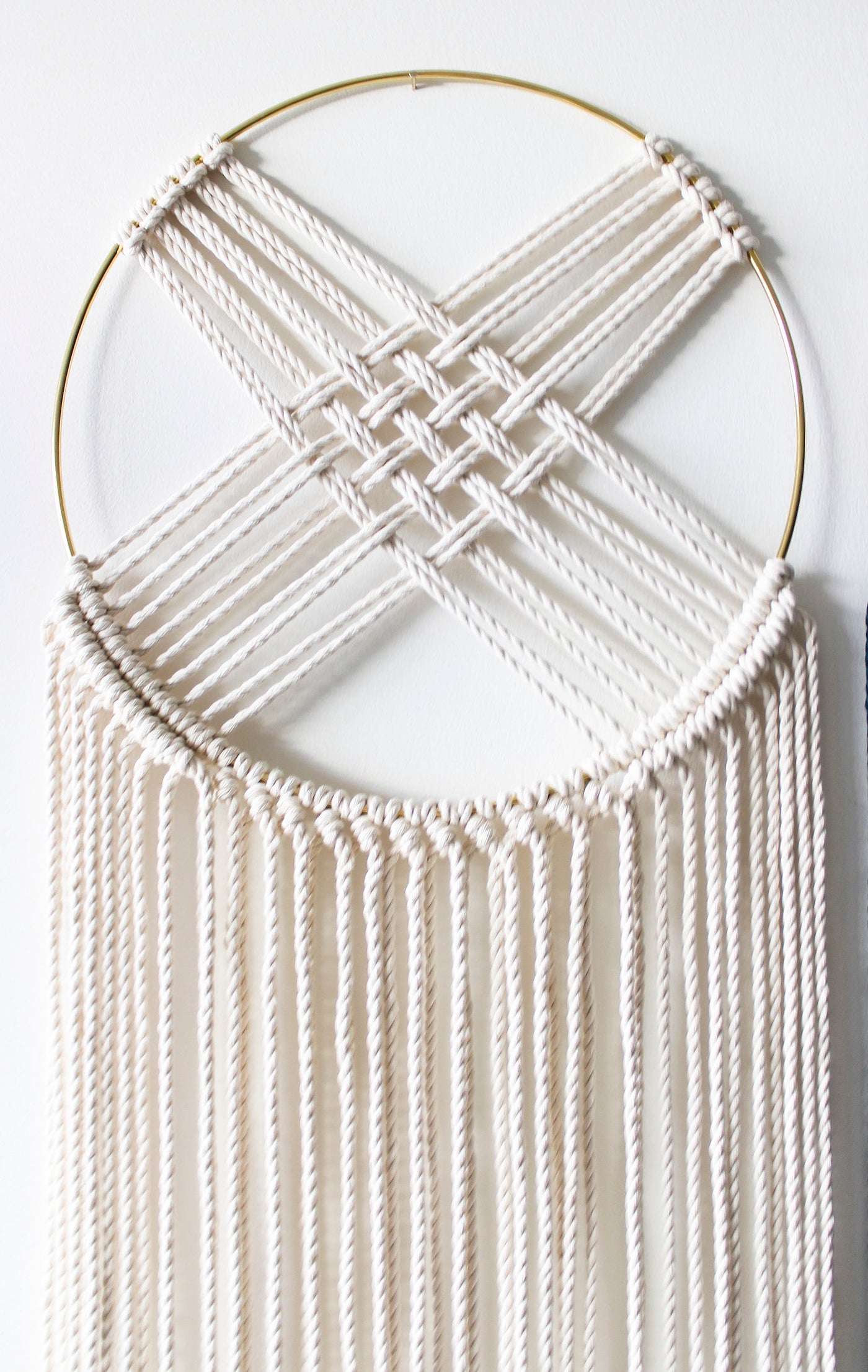 Macrame dreamcatcher wall hanging with gilded brass hoop and long ivory fringe.