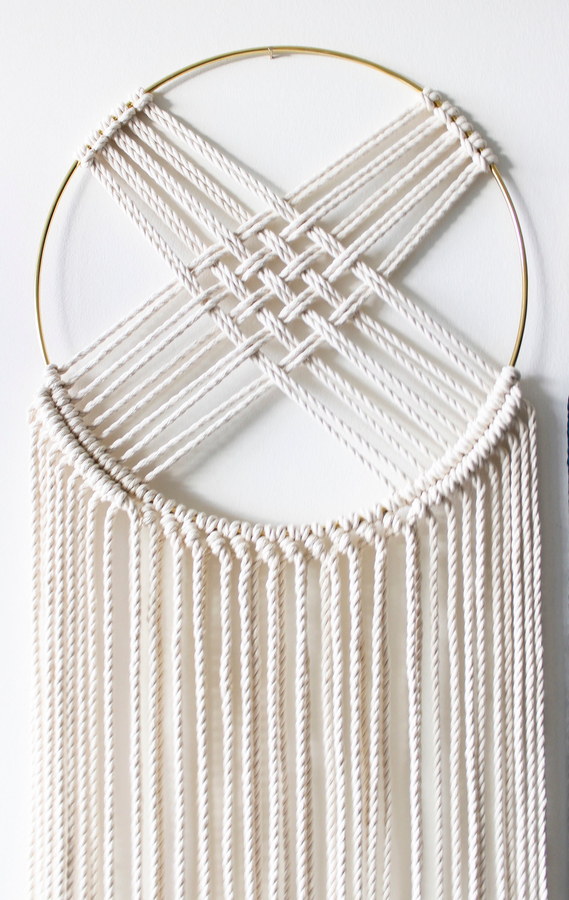 Macrame dreamcatcher wall hanging with gilded brass hoop and long ivory fringe.
