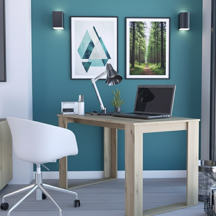 Modern home office with a wooden desk, laptop, lamp, and decorative items against a teal wall.