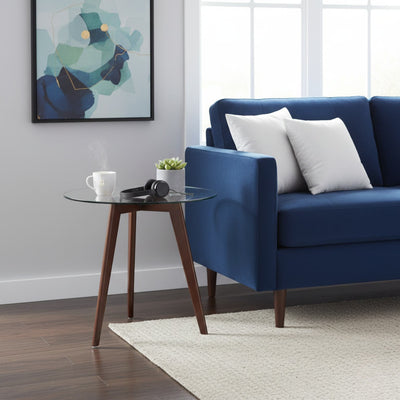 Modern living room with a blue sofa, glass side table, and abstract art on the wall.