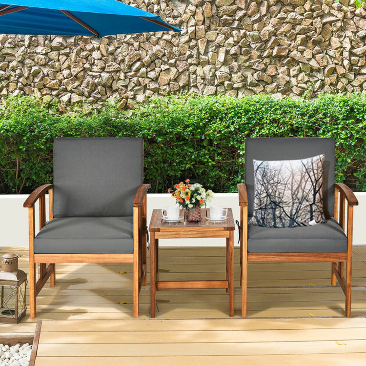 Outdoor furniture set with two chairs and a small table on a wooden deck against a stone wall.
