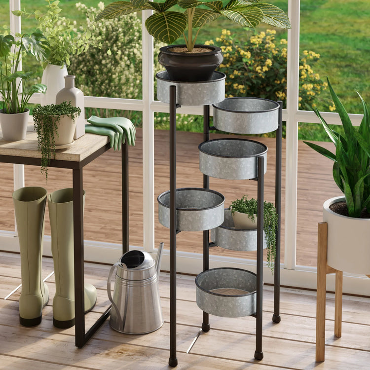 Outdoor setting with a plant stand, potted plants, and gardening tools on a wooden deck.