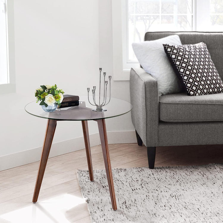 Round tempered glass dining table with 8mm beveled edge and warm oak tripod base in a bright living room.