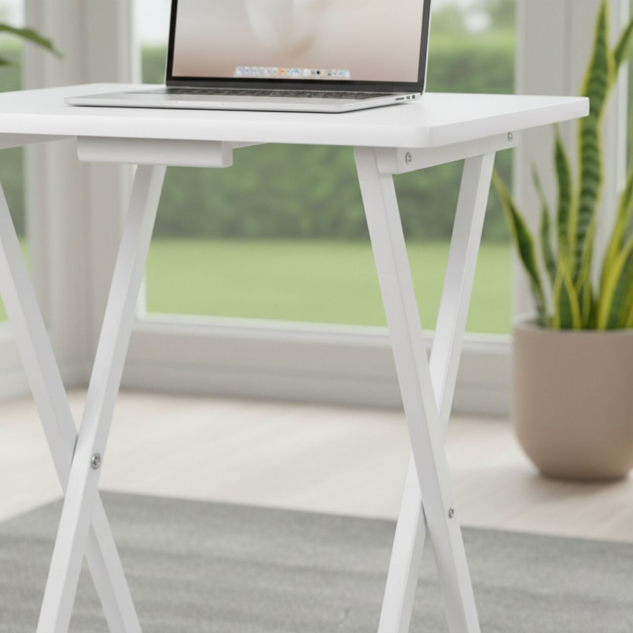 Set of 2 white folding TV tray tables with solid wood finish and X-frame legs, laptop on top.