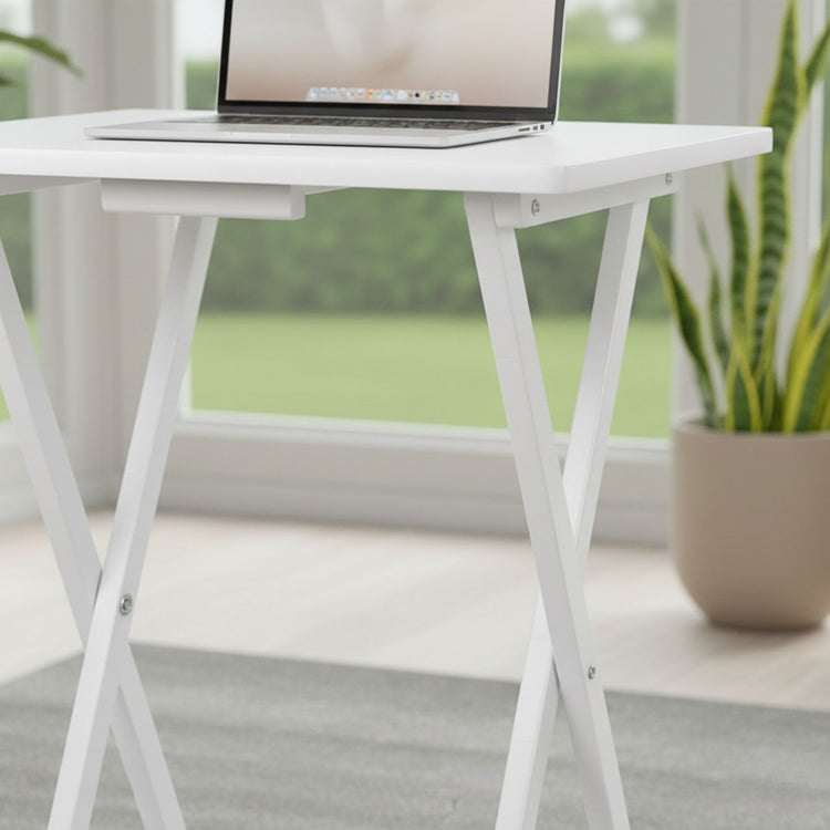 Set of 2 white folding TV tray tables with solid wood finish and X-frame legs, laptop on top.