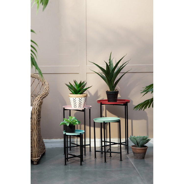 Set of small tables with potted plants against a neutral wall.