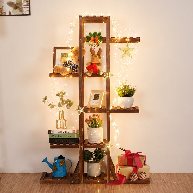 Six-tier pine wooden plant stand with fairy lights, greenery, books, and gift boxes.
