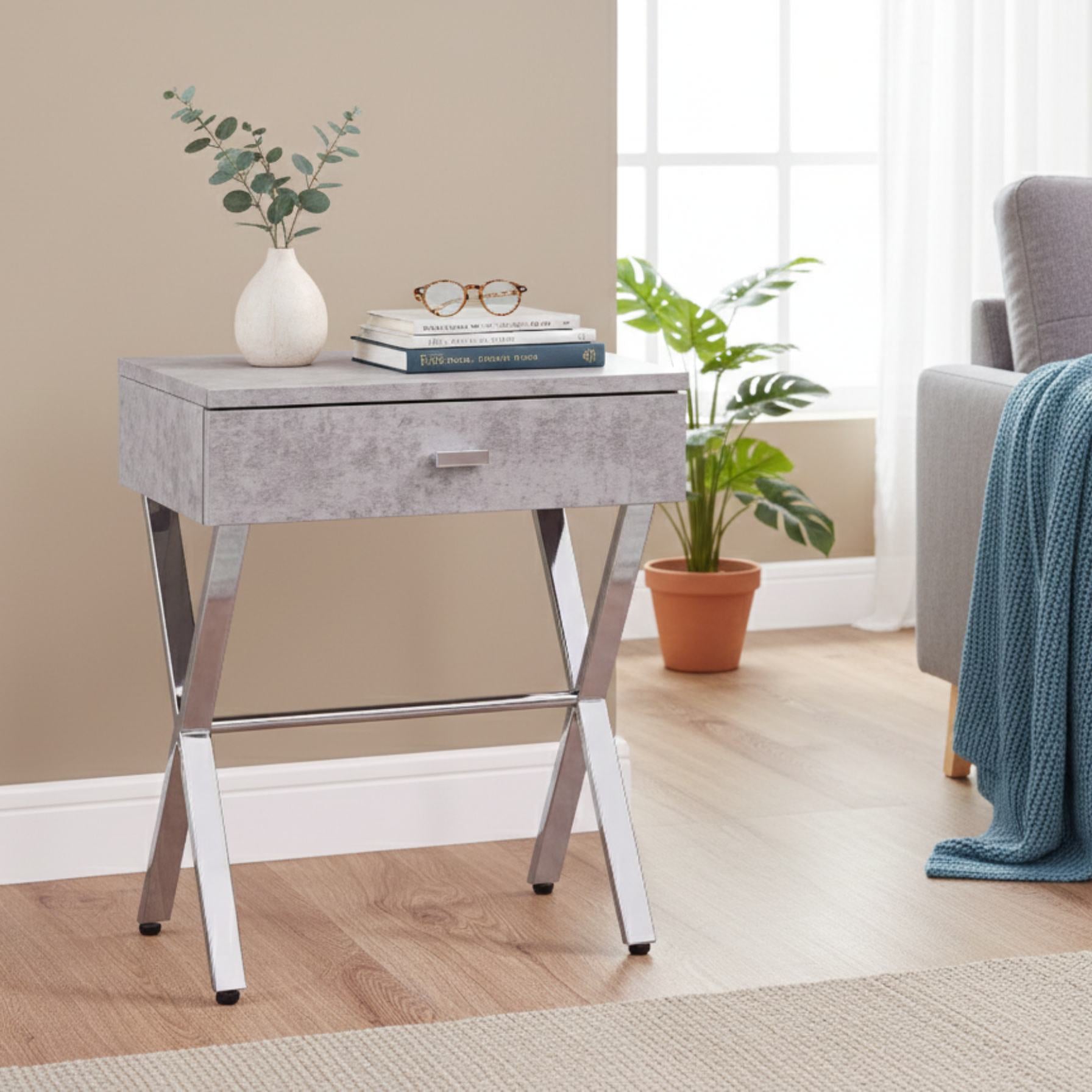 Sleek dark taupe finish and chrome metal accent table with a drawer, chrome legs, and a vase on top.