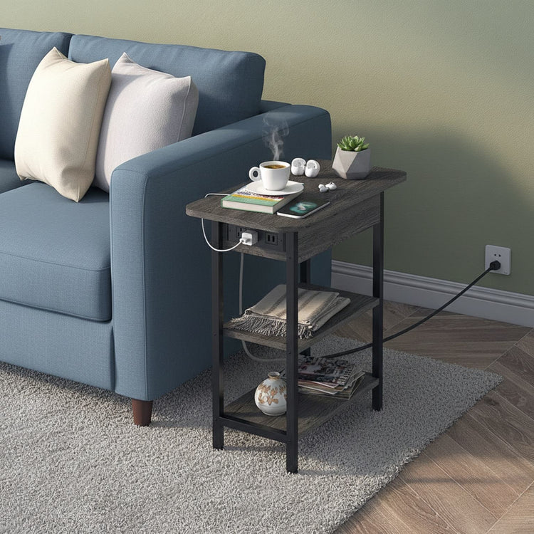 Small black side table next to a blue sofa with a cup, books, and a plant on it.