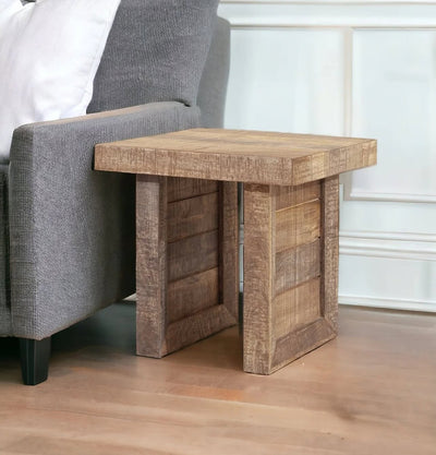 Solid wood butcher-block end table with warm finish beside a sofa, featuring block-style legs.