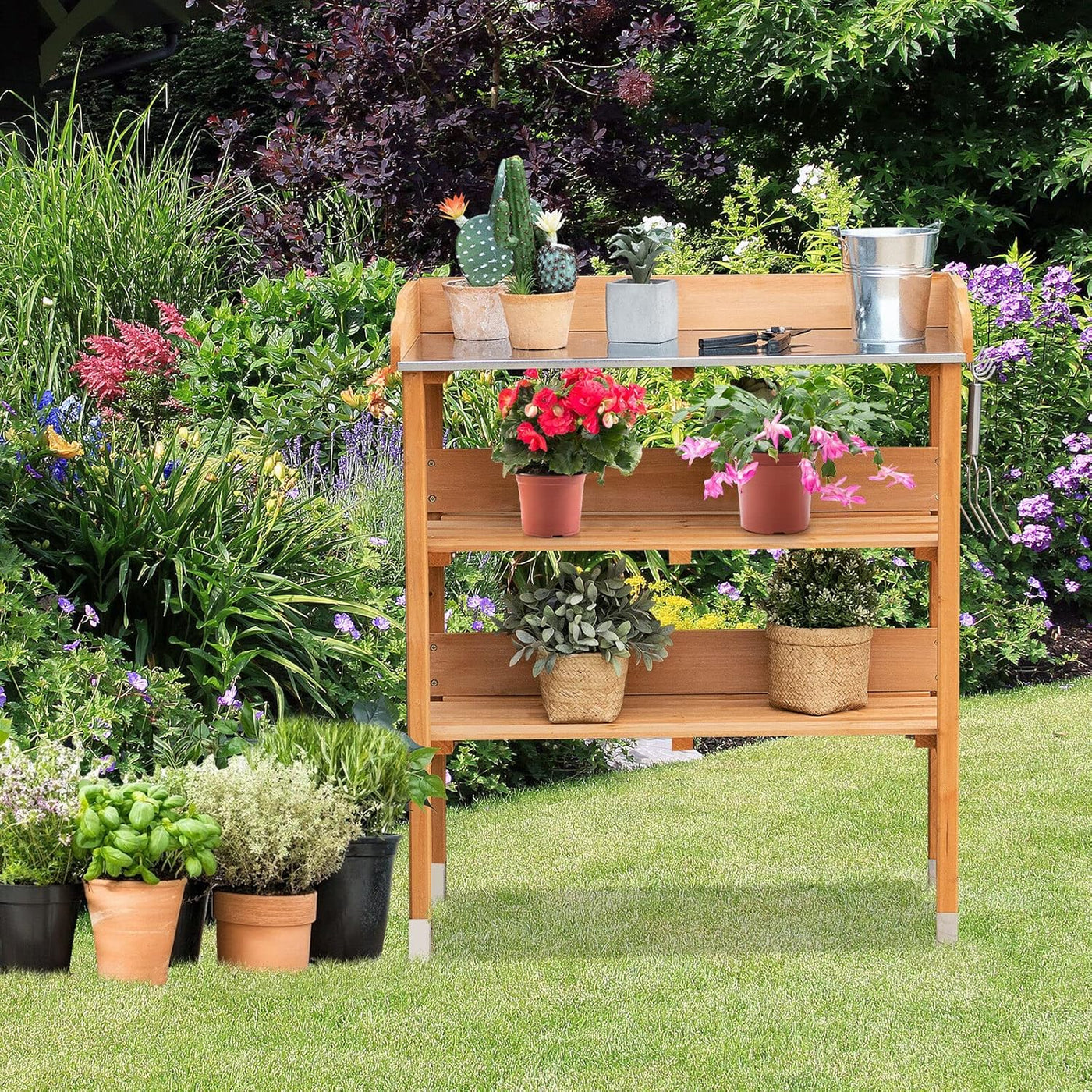 Solid wood outdoor garden bench table with bottom storage shelves and metal top, shown with potted plants.