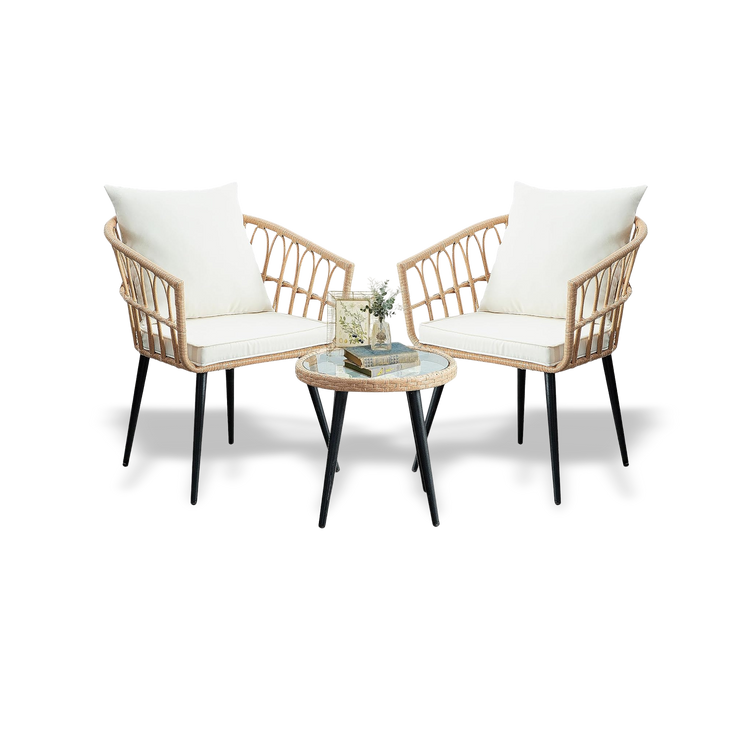 Two wicker chairs with white cushions and a matching table on a white background