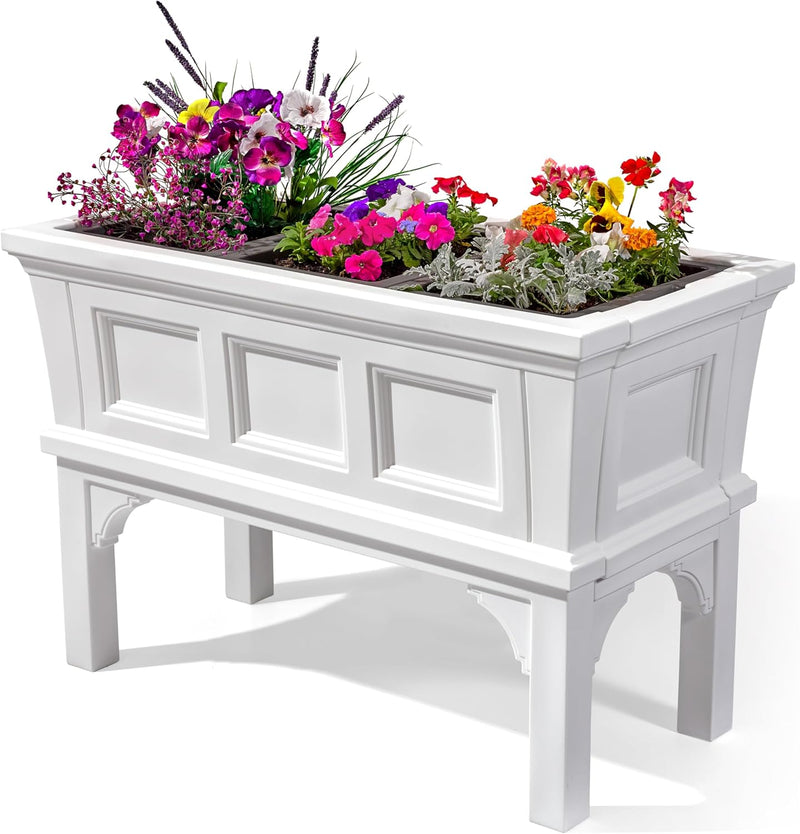 White rectangular raised garden bed planter box with removable trays and elevated legs, filled with colorful flowers.