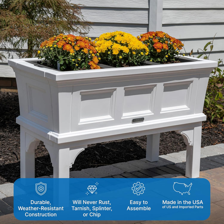 White rectangular raised garden bed planter box with removable trays on elevated legs, filled with yellow and orange chrysanthemums.