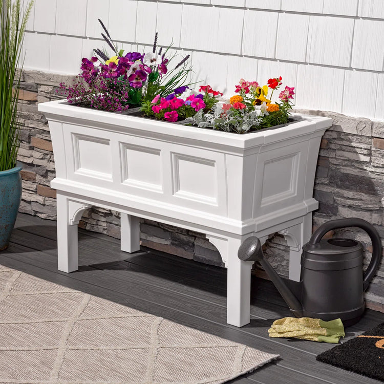 White rectangular raised garden bed planter with removable trays on an elevated stand, colorful flowers.